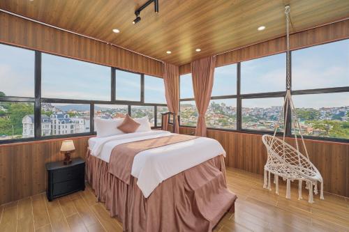 a bedroom with a bed in a room with windows at Luxury Hotel Dalat in Xuan An