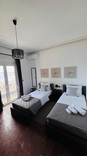 ein Schlafzimmer mit zwei Betten und einem großen Fenster in der Unterkunft The Waves Studio in Patras