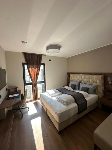 a bedroom with a bed and a desk and a window at Intergroup Business & Design Hotel Ingolstadt in Kösching