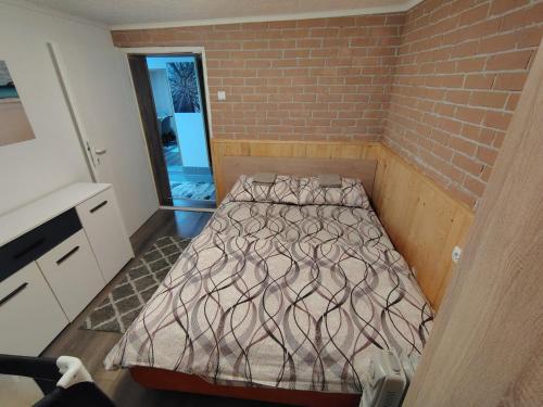 a bed in a room with a brick wall at Vikendica sa bazenom"Mila"Banja Topilo in Banja Topilo