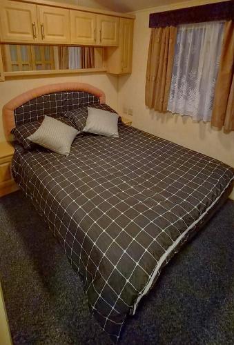 a bed in a small room with a plaid bedspread at MOLLIES DEN 2 8 Berth 3 Bedrooms The Grange Holiday Park INGOLDMELLS in Ingoldmells
