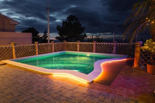 a swimming pool with lights in a backyard at night at Appartamenti Anzà in Capo dʼOrlando