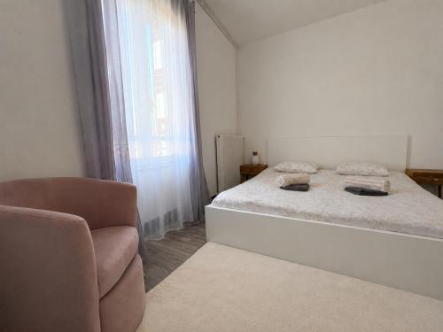 a white bedroom with a bed and a chair at Le Balcon in Montargis