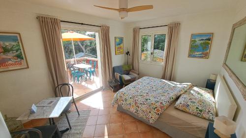 a bedroom with a bed and a table with an umbrella at L'Alizé du Levant in Île du Levant