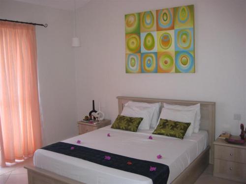a bedroom with a large white bed with two pillows at Villa Pupunu 1 in Grand Gaube