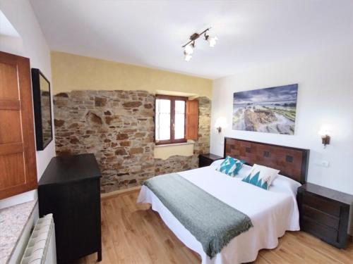 a bedroom with a bed and a stone wall at Apartamentos Navalin in Tapia de Casariego