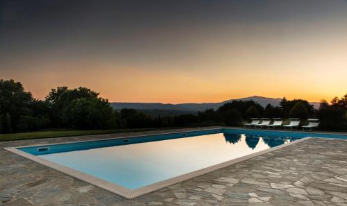 a swimming pool with a sunset in the background at Agriturismo I Gergoni in Monteleone dʼOrvieto