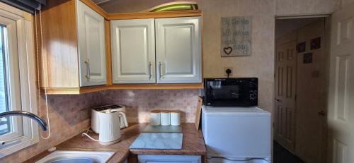 a kitchen with a white refrigerator and a microwave at MOLLIES DEN 2 8 Berth 3 Bedrooms The Grange Holiday Park INGOLDMELLS in Ingoldmells