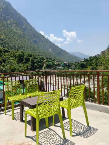 four chairs and a table on a balcony with a view at The Morchella House Tirthan Valley in Gushaini