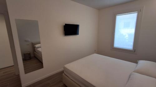 a white room with a couch and a mirror at VELORA STAYS Florinas in Lido di Jesolo