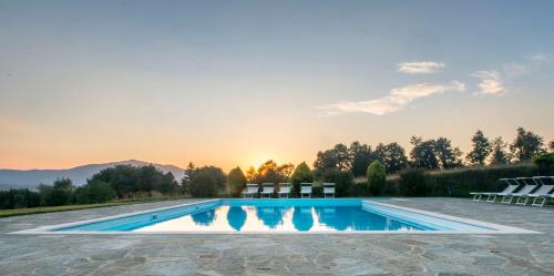 a pool with chairs and the sunset in the background at Agriturismo I Gergoni in Monteleone dʼOrvieto