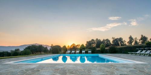 une piscine avec des chaises et le coucher du soleil en arrière-plan dans l'établissement Agriturismo I Gergoni, à Monteleone dʼOrvieto