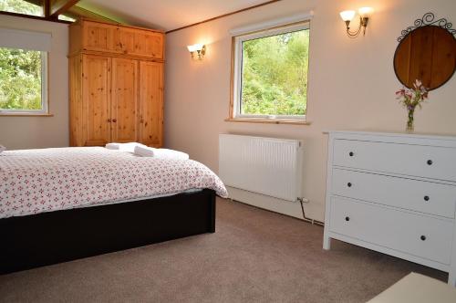 a bedroom with a bed and a dresser and two windows at Cockleshell Lodge in Otter Ferry