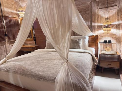 a bedroom with a bed with a mosquito net at Joglo Ulu Home in Uluwatu