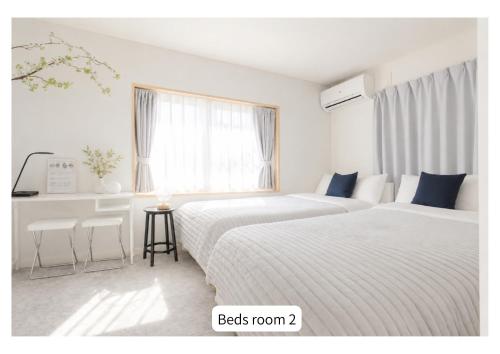 two beds in a white room with a window at Quiet Myoden-Disney & Tokyo Sightseeing Base in Ichikawa