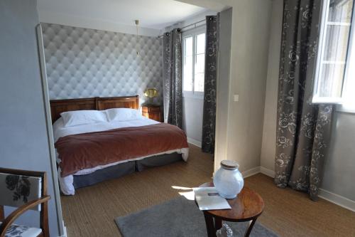 a bedroom with a bed and a table and windows at MAISON DE MARQUAY-MAISON D'HOTES in Marquay