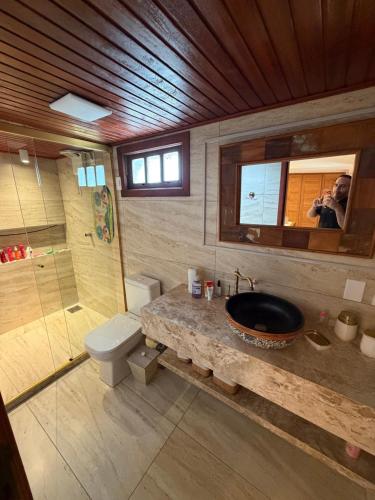 a man taking a picture of a bathroom with a sink at A casa do vale in Bananeiras