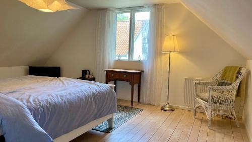 a bedroom with a bed and a chair and a window at Åkeslund in Hörby