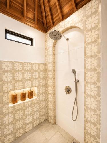 a shower stall in a bathroom with tiles at Joglo Ulu Home in Uluwatu
