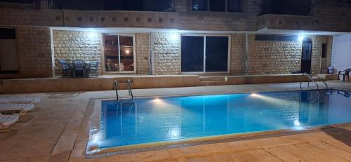 a large swimming pool with blue water at night at Honey Chalet in Al Khayyām