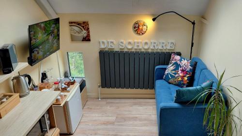 a living room with a blue couch and a kitchen at B&B De Schorre in Boom
