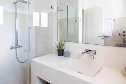 a white bathroom with a sink and a shower at Villa NS in Perdika