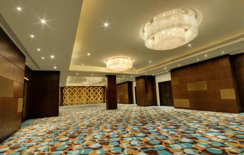 una grande sala da ballo con due lampadari a braccio e una grande stanza di Hotel Platinum a Rajkot