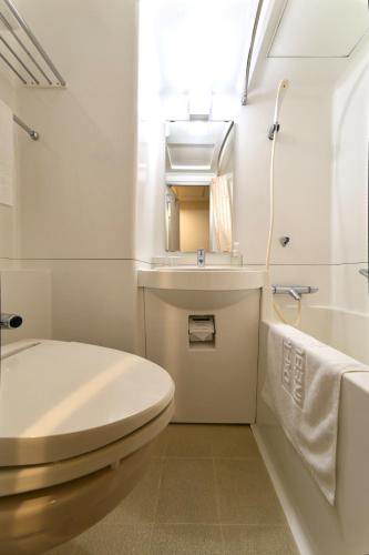 a bathroom with a toilet and a sink and a mirror at Daiichi Inn Ikebukuro in Tokyo