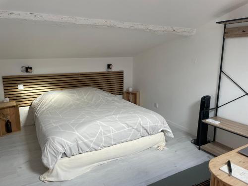 a bedroom with a white bed with a wooden headboard at L'entre deux M in Saint-Loubès