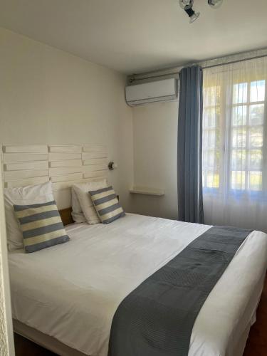 a bedroom with a large white bed with two pillows at Hôtel Castel Saint Anne in Le Castellet