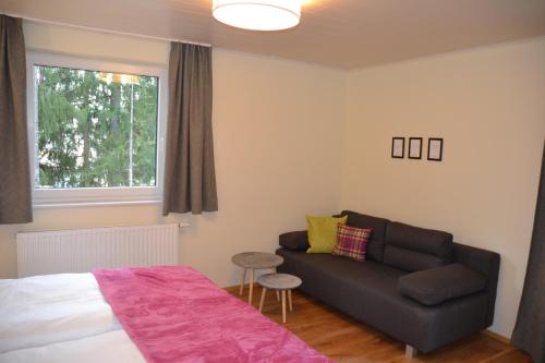 a bedroom with a bed and a couch and a window at Pension Adlerhorst in Ramsau am Dachstein
