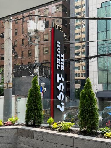 a sign in front of a building with two trees at The hotel 1997 - 더호텔 1997 in Seoul