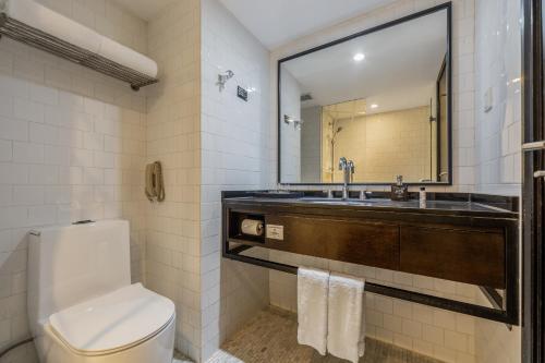 a bathroom with a toilet and a sink and a mirror at Beijing New World Centre Tongpai Hotel in Beijing