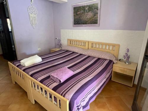 a bedroom with a large bed with purple sheets at Nonna Antonietta in San Teodoro