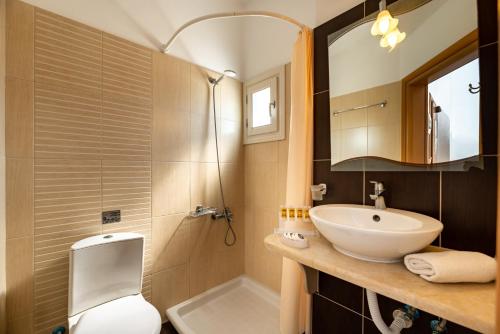 a bathroom with a sink and a toilet and a mirror at Stelios Place in Perissa