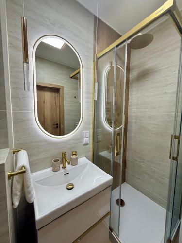 a bathroom with a sink and a shower and a mirror at Justinrent PALATIUM 31 in Legnica