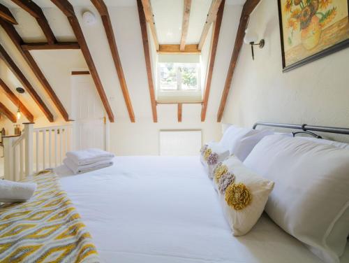 a large white bed in a room with a window at Miranda Cottage in Polperro