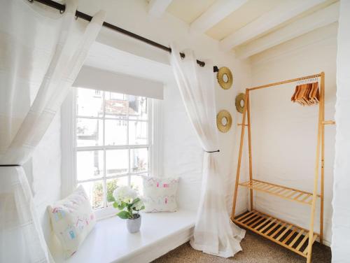 a white room with a window and a window seat at Miranda Cottage in Polperro