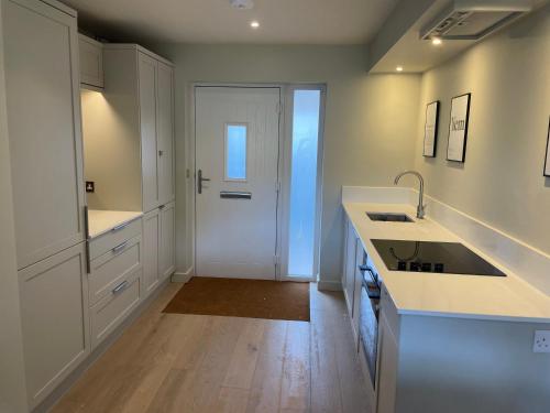 a kitchen with white counters and a white door at Riverside Stay in Morpeth