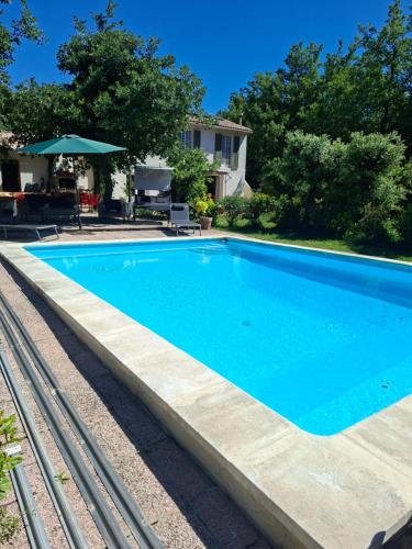 een zwembad met blauw water in een tuin bij LES CHÊNES in Villes-sur-Auzon