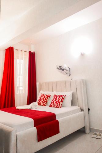 a bedroom with a bed with red curtains at Cozy studio at Kisimani Heights Apartment Mombasa in Mombasa