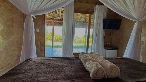a bedroom with a bed with a large window at Pousada Nitxi Awêry in Caraíva