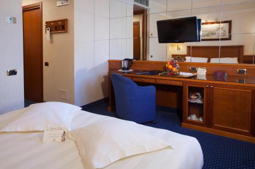 a hotel room with a bed and a desk with a television at Hotel Berna in Milan