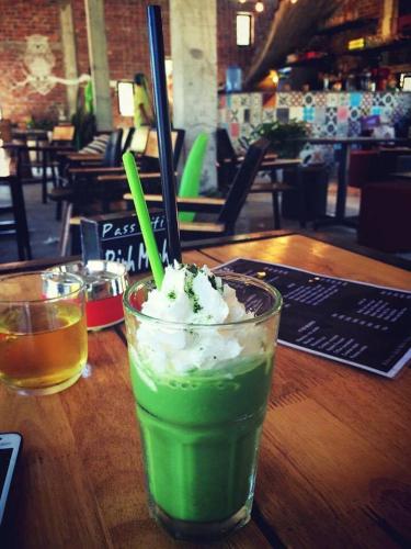 a green drink sitting on a wooden table with a drink at Binh Minh Dien Chau Hotel in Diễn Châu