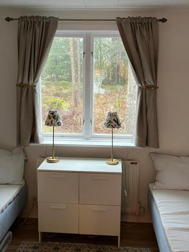 Ein Schlafzimmer mit zwei Lampen auf einer Kommode vor einem Fenster in der Unterkunft Kalvsvik in Värmdö