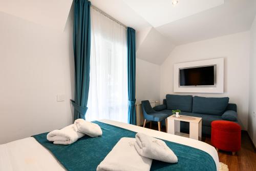 a bedroom with a bed and a blue couch at One Luxury Suites AKUSTIK - 3 minuta peške do Jezera in Zlatibor