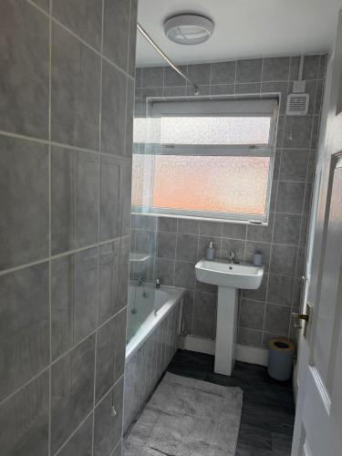 a bathroom with a tub and a sink and a window at Stylish 4BR Home - Sleeps 7 - Parking & WiFi in Nottingham