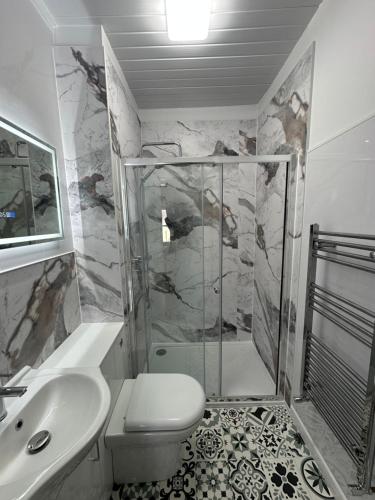 a bathroom with a shower and a toilet and a sink at Myrtle House Hotel in Tenby