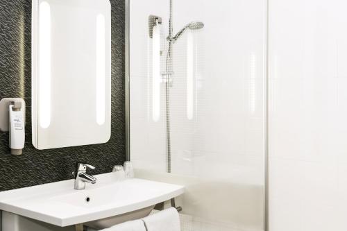 a white bathroom with a sink and a shower at ibis Mulhouse Ile Napoleon in Sausheim