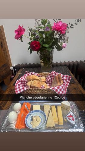 a table with a plate of food and a vase with flowers at Le magnolia in Épieds